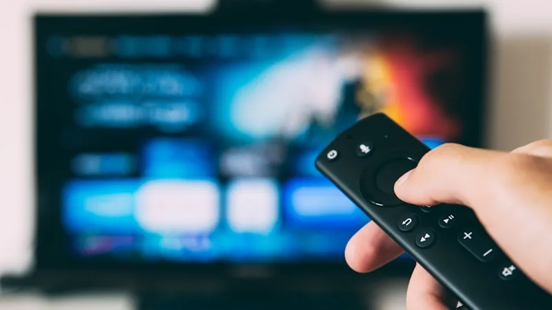 Remote control pointed at a television screen showing a streaming interface, representing IPTV USA live TV streaming